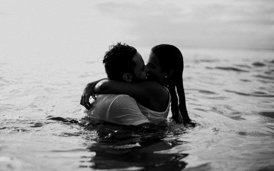 man and woman kissing together on body of water