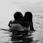 man and woman kissing together on body of water